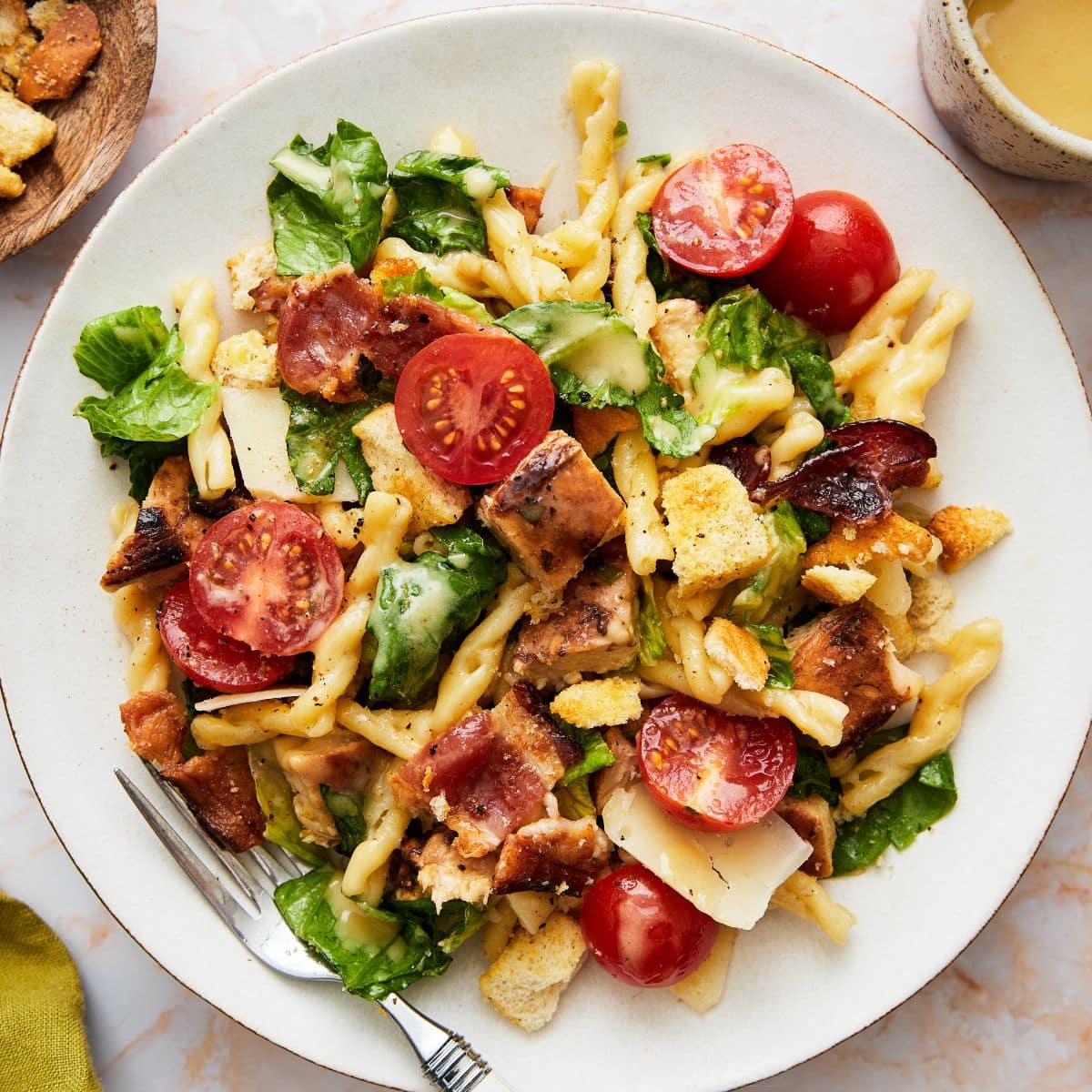 Chicken caesar pasta salad on a white plate.