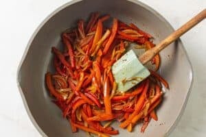 Mixing peppers and onions with seasoning.