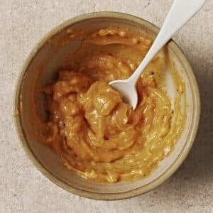 Lemon butter sauce in a bowl with a white spoon.