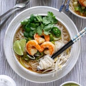 Overhead shot of shrimp pho in a bowl with chopsticks.
