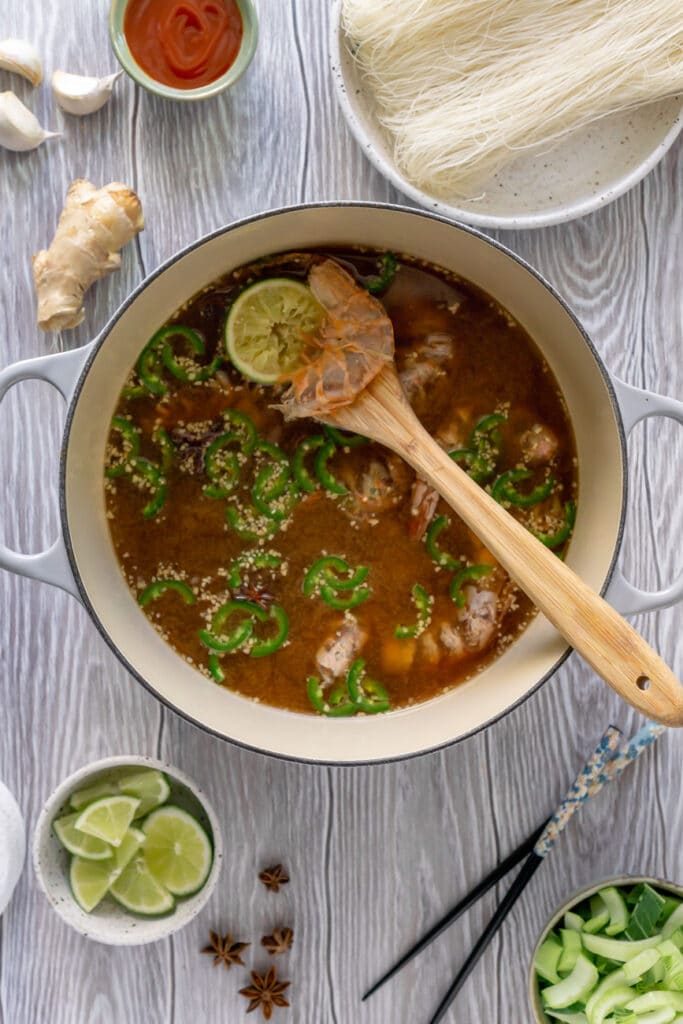 Stirring shrimp pho in a pot.