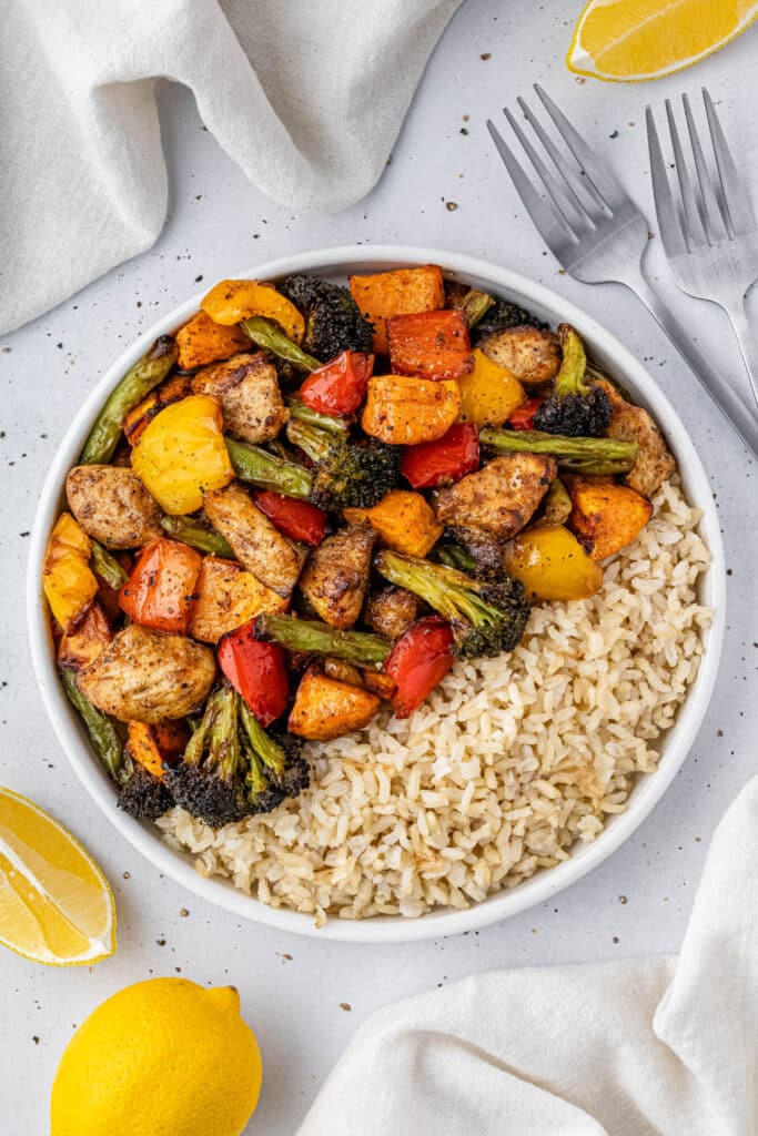 chicken and vegetables and rice sit on a bowl under a white table