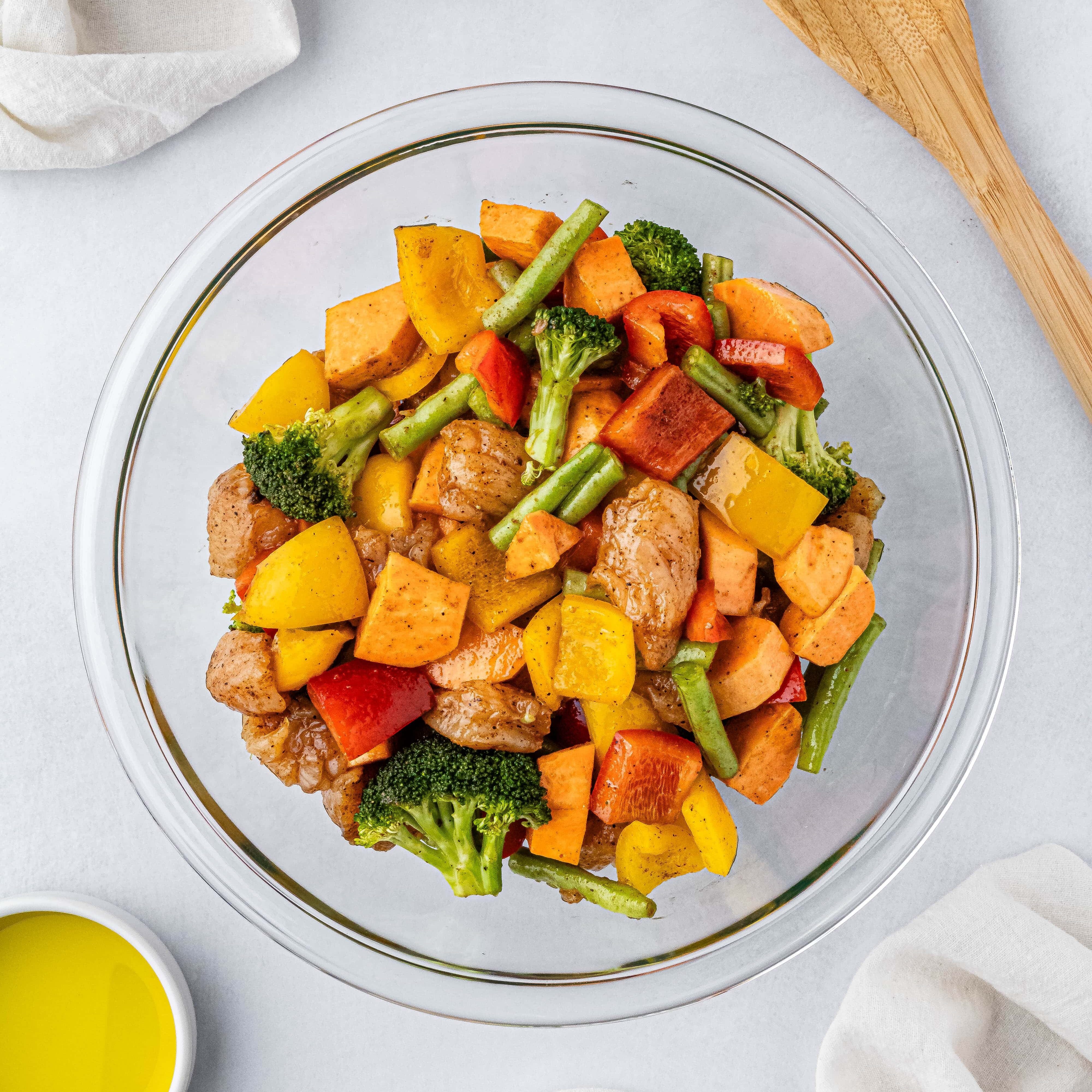seasoned raw chicken and cut up vegetables sitting in a glass bowl