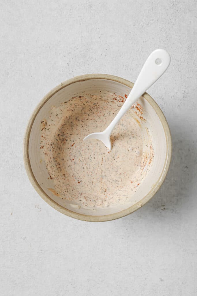 Sauce mixed in a bowl with a white spoon in it.