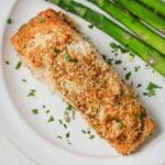 Cooked panko salmon on a white plate with asparagus.