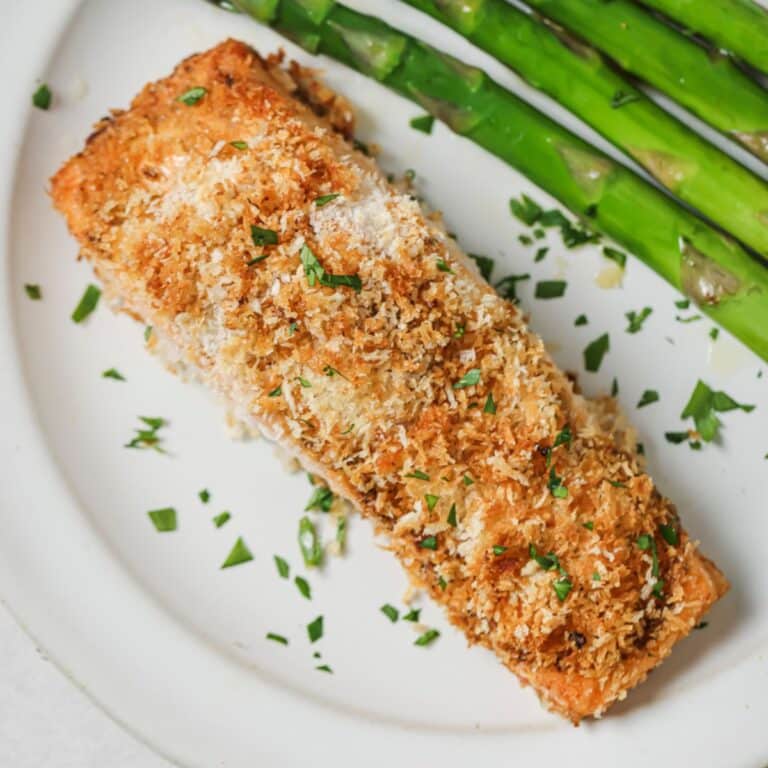 Cooked panko salmon on a white plate with asparagus.
