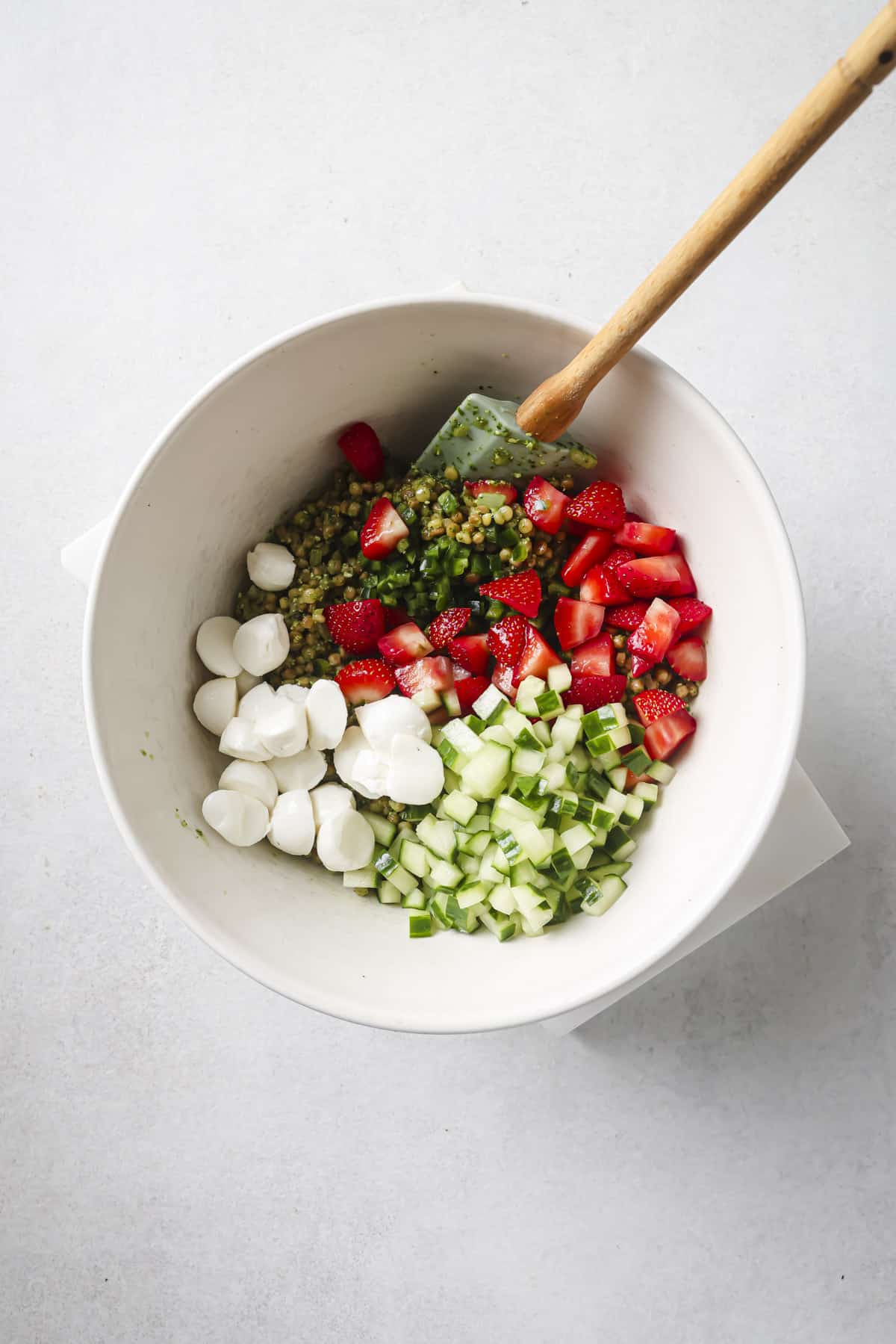 Stirring strawberries, cucumbers and mozzarella into couscous.