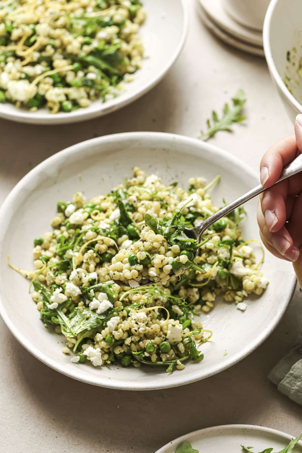 Hand holding a fork to get a forkful of couscous salad.