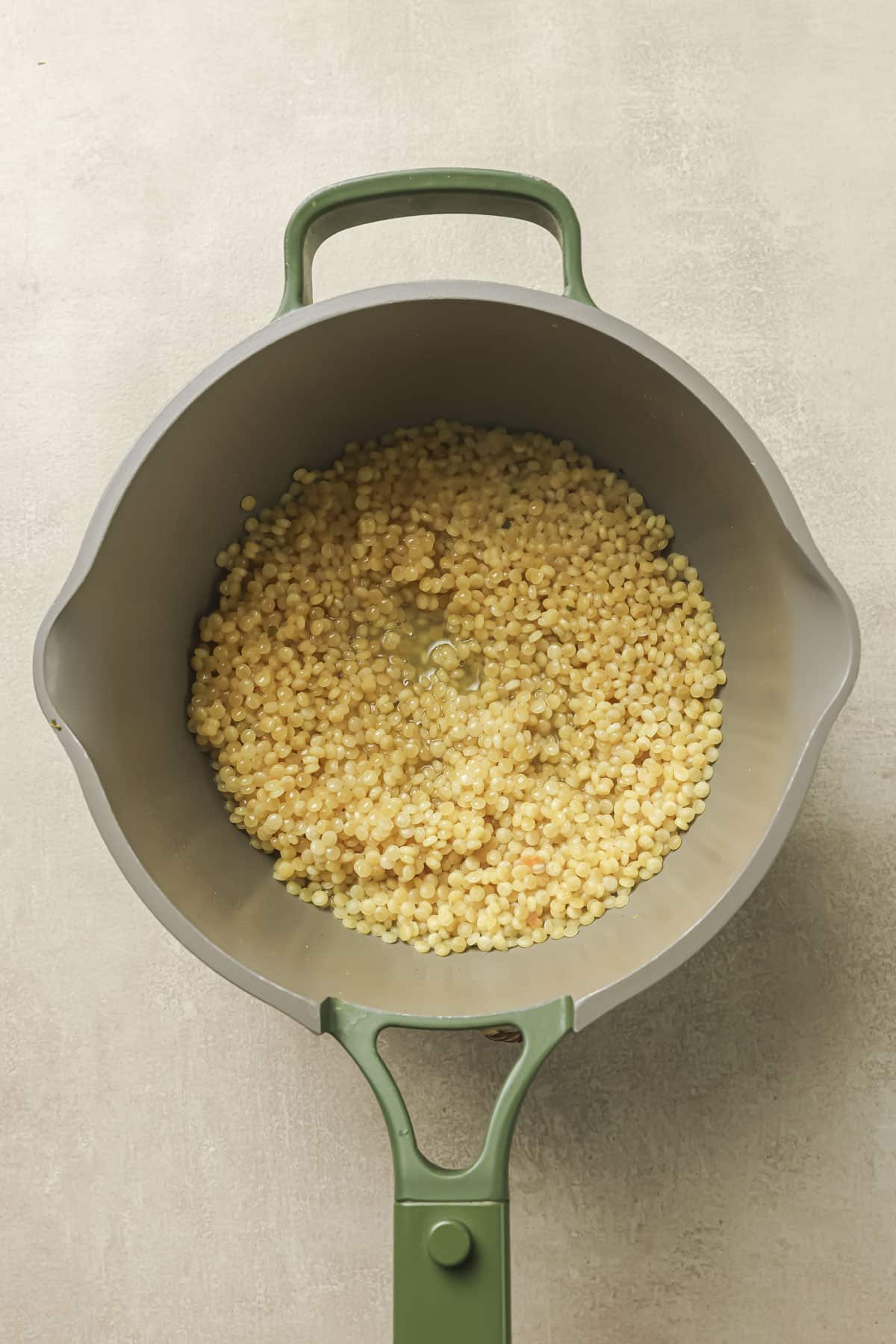 Cooking couscous in chicken broth in a large pot.