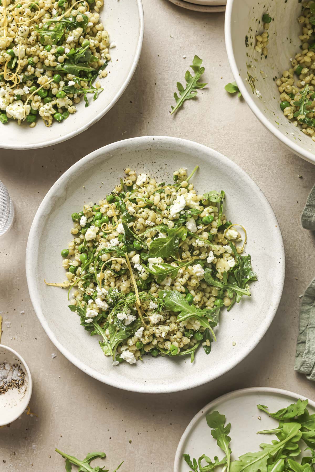 Spring pea pearl couscous salad served on a white plate.