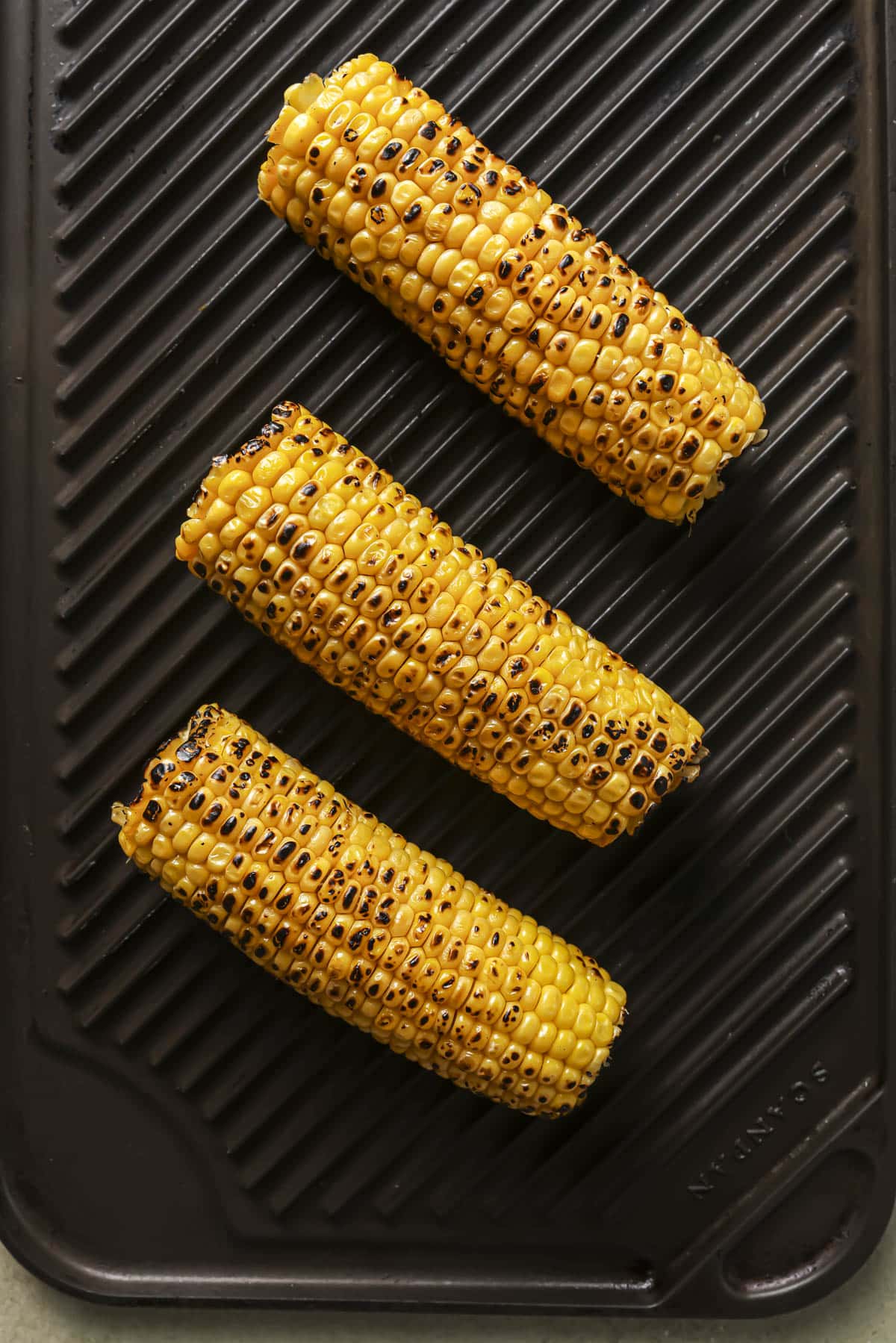 Charring corn-on-the-cob on a grill pan.
