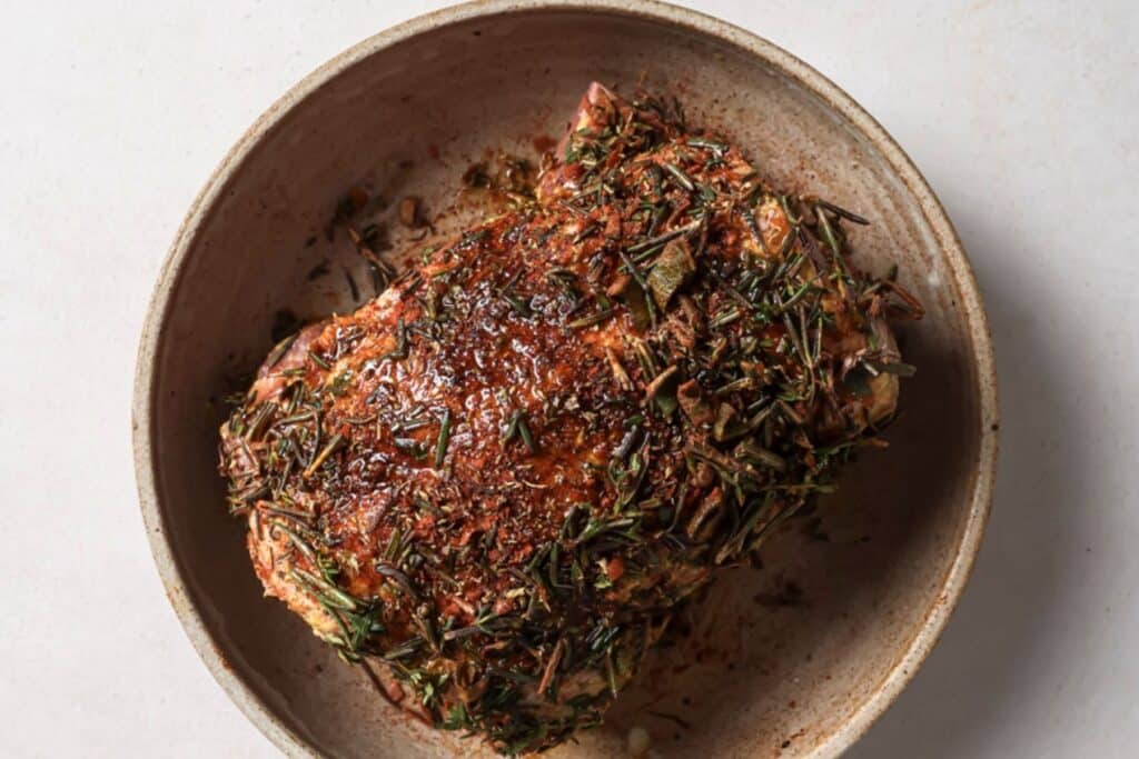 Coating beef brisket with herbs and spices.