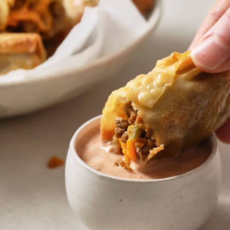 Dipping a cheeseburger egg roll in burger sauce.