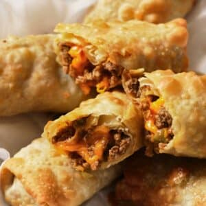 Halved air fryer cheeseburger egg rolls stacked on a serving platter.