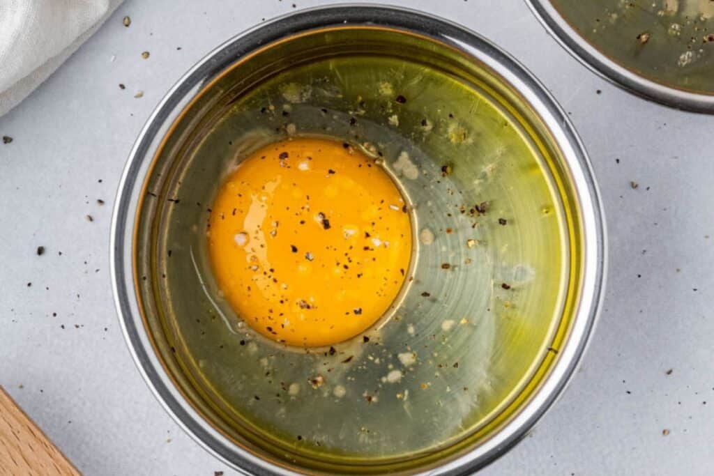 Adding salt and pepper to egg in mini muffin tin.