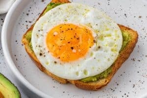 Adding air fryer fried egg to avocado toast.
