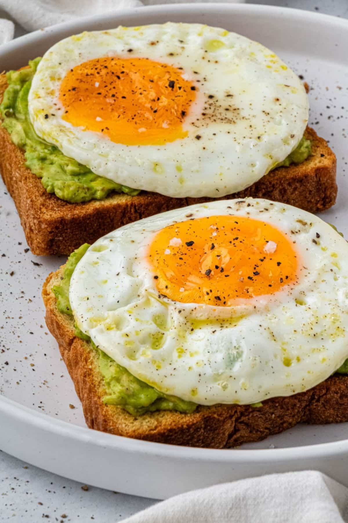 Two air fryer fried eggs over avocado toast.