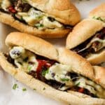 Air fryer philly cheesesteak on a plate with other sandwiches in the background.