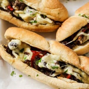 Air fryer philly cheesesteak on a plate with other sandwiches in the background.