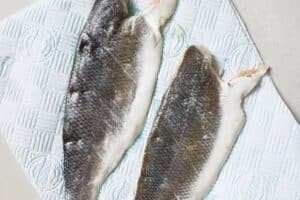 Scoring sea bass fillets on a paper towel.