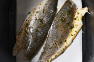 Uncooked sea bass fillets in the air fryer basket.