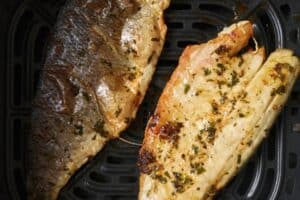 Flipping sea bass fillets in the air fryer basket.