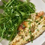 Sea bass served with a side of arugula.