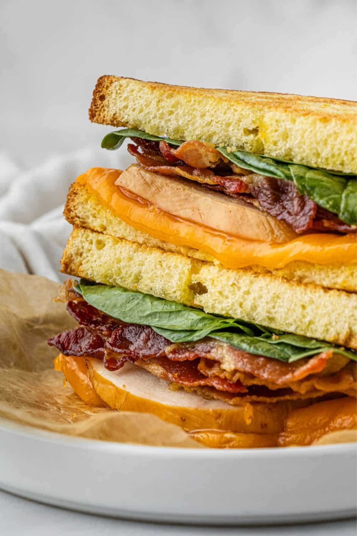 Two halves of a turkey sandwich stacked on top of each other on a plate.