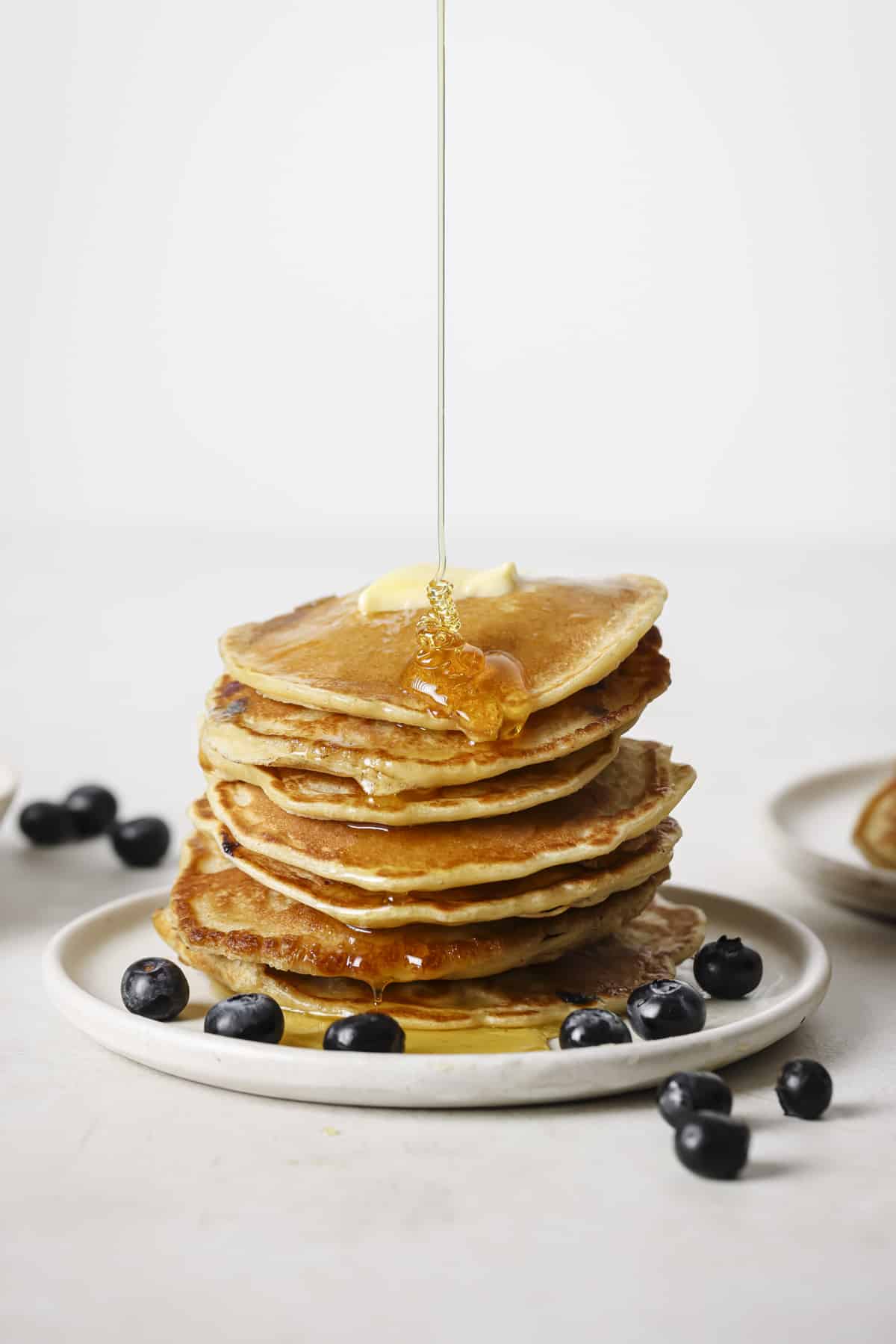 Drizzling syrup over a stack of blueberry banana pancakes.