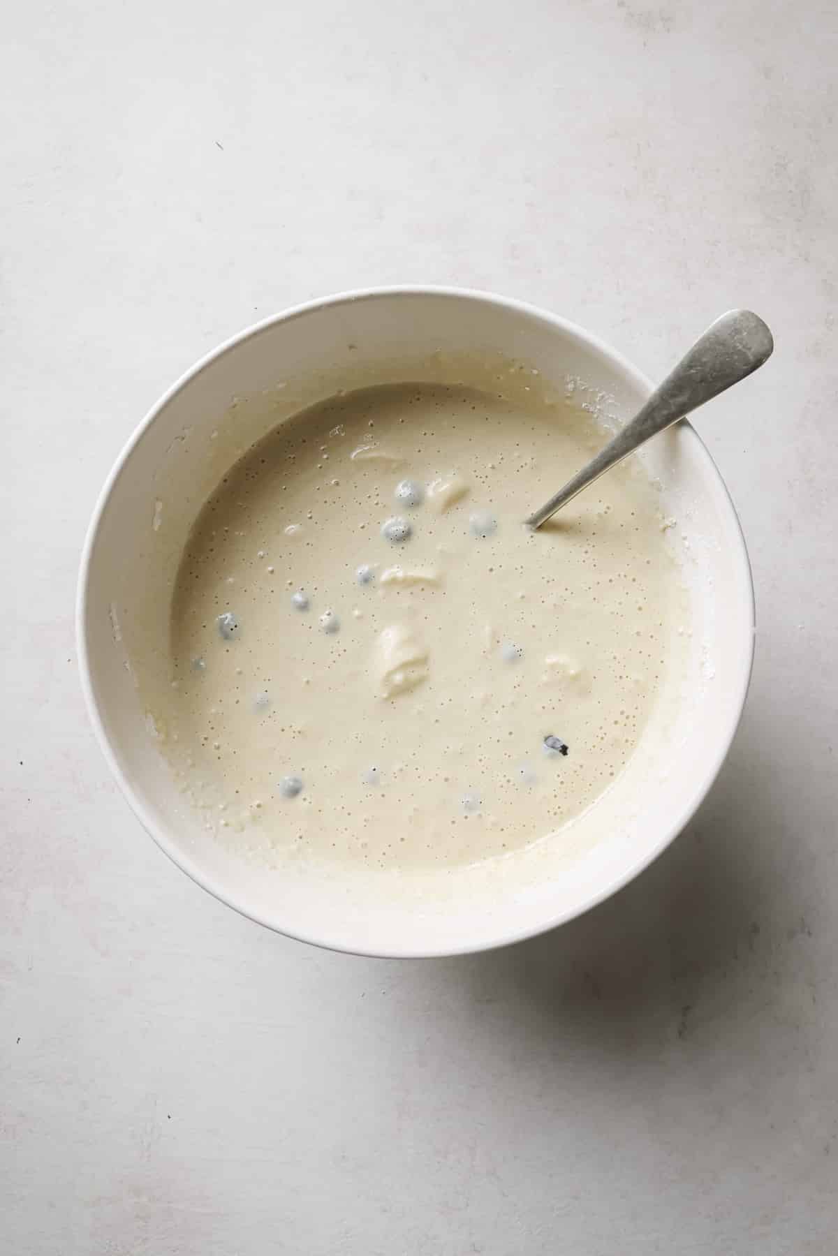 Stirring in banana slices and blueberries to pancake batter.