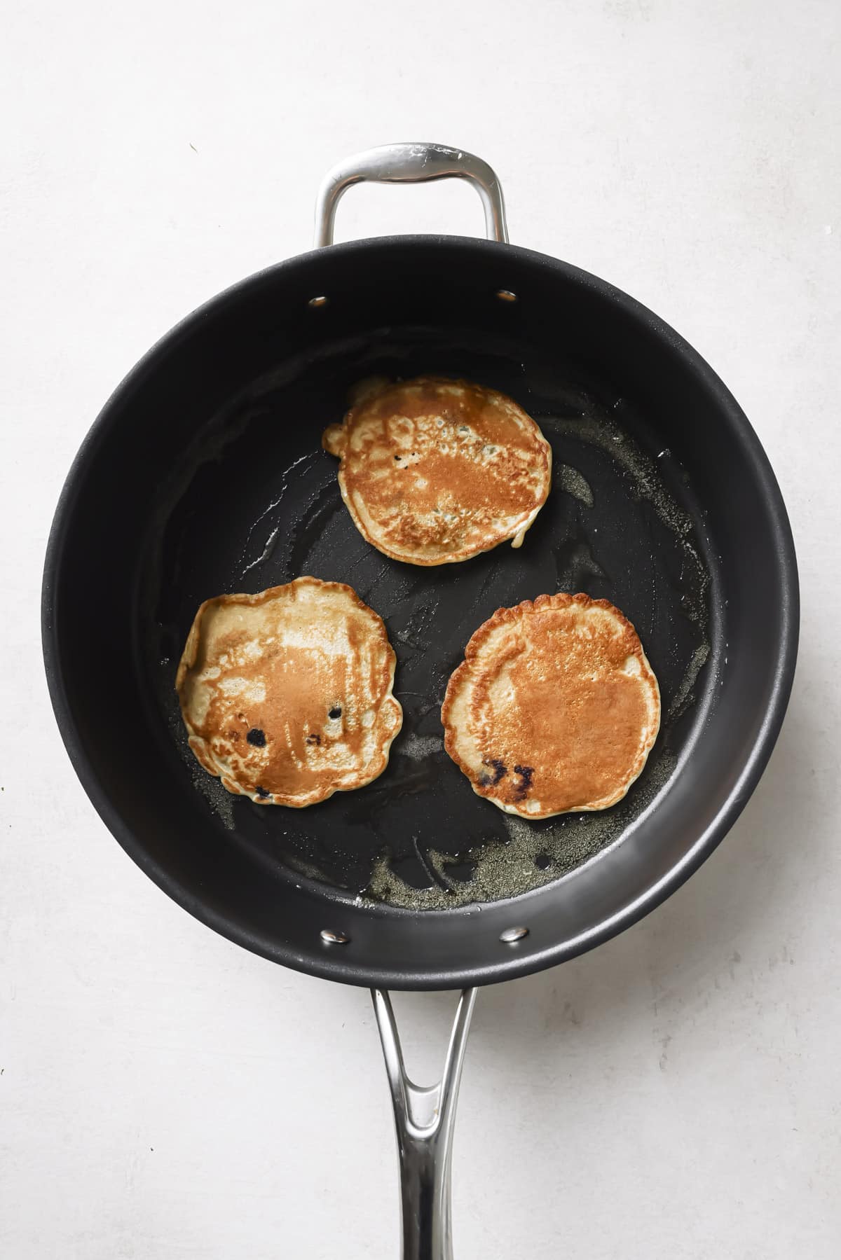 Cooking blueberry banana pancakes in a skillet.