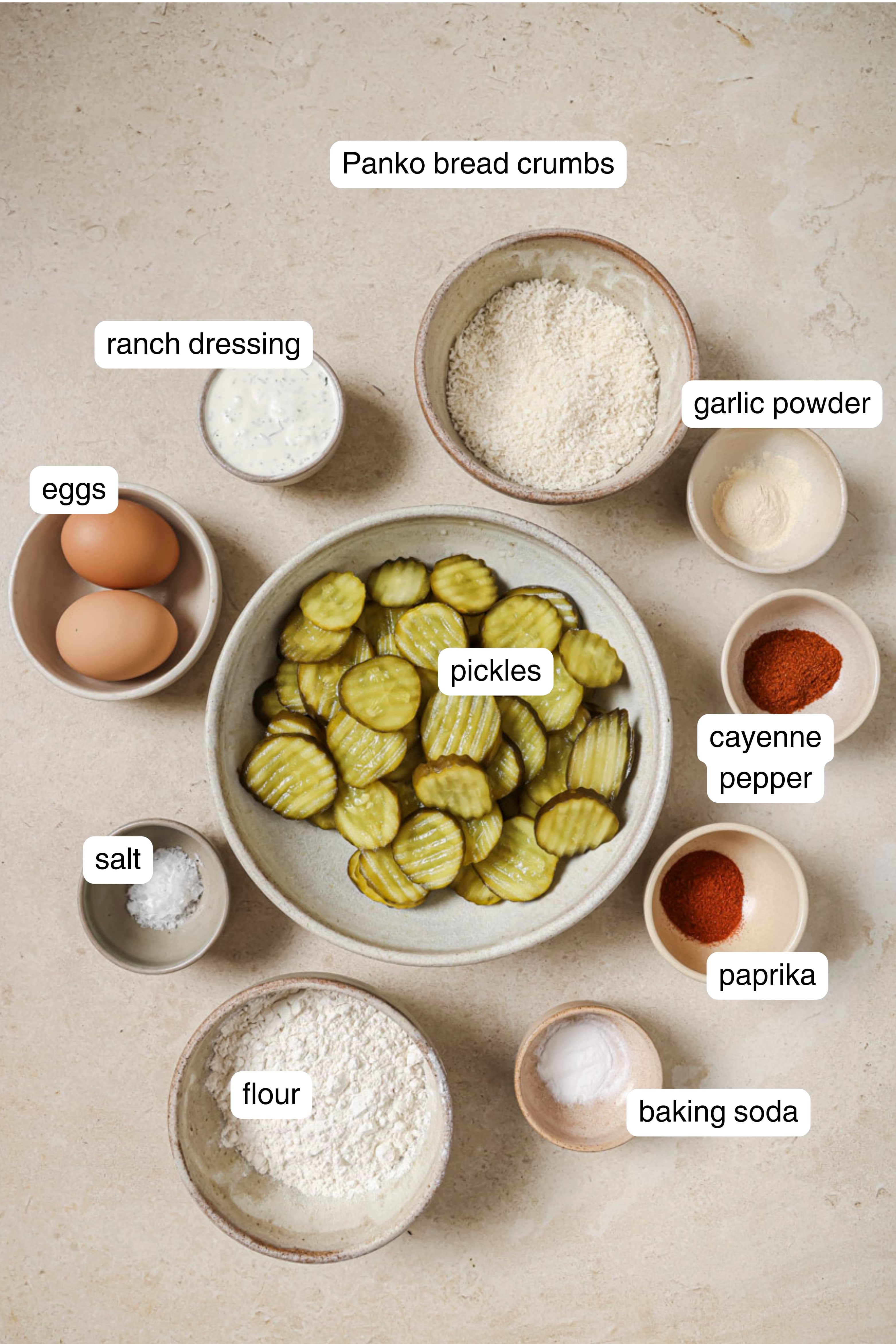 Pickles, flour, spices, eggs, ranch dressing, and panko in small ingredient bowls.