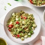 Israeli couscous salad topped with strawberries in a white bowl.