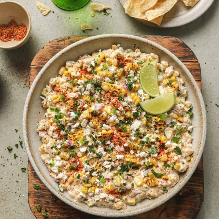 Street corn dip garnished with slices of lime.
