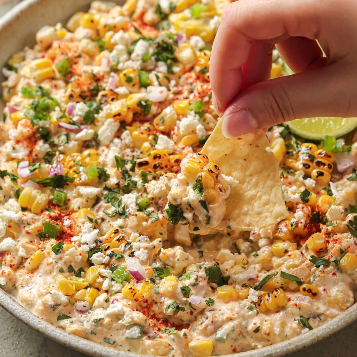 Dipping a chip in mexican street corn dip.