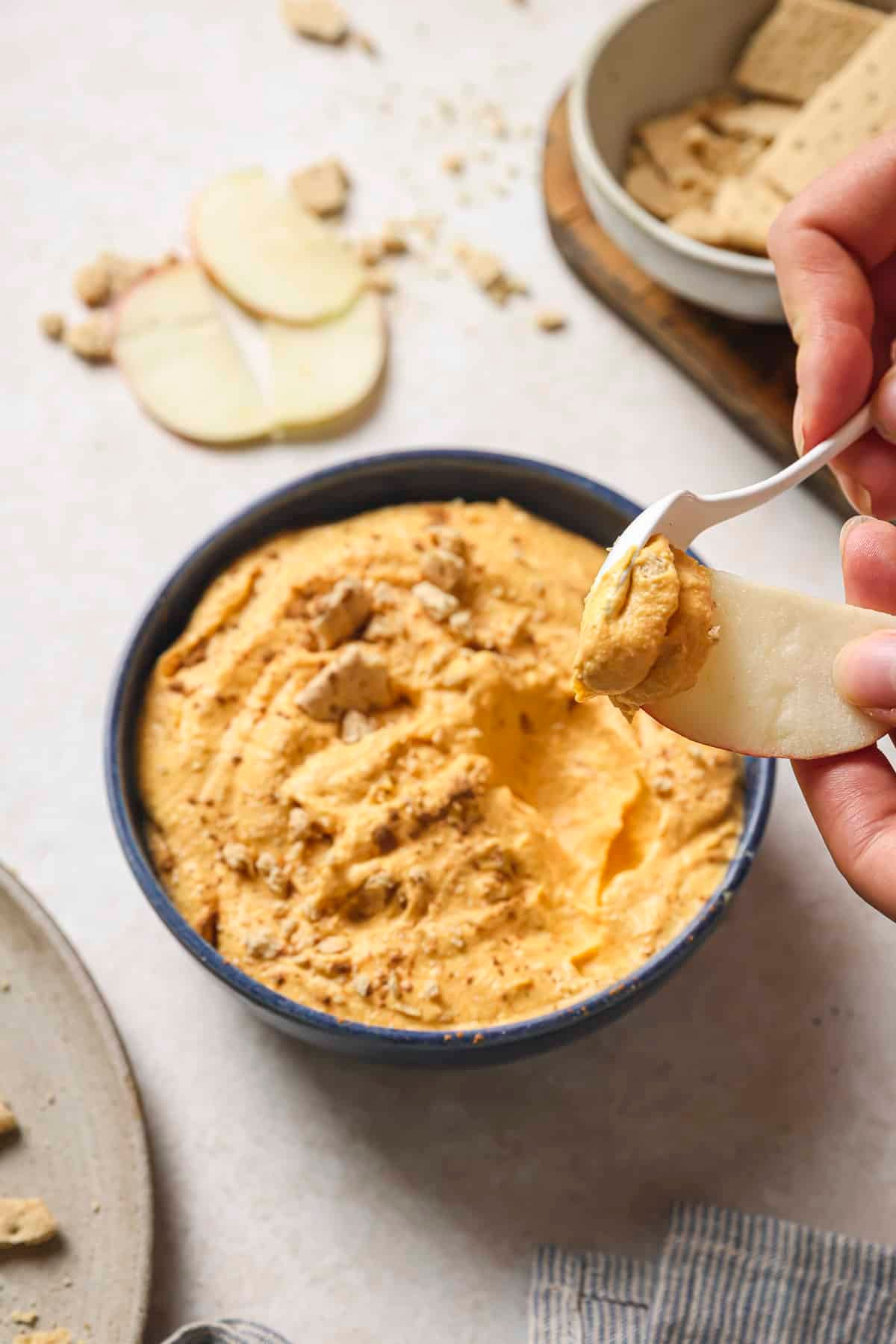 Spooning pumpkin pie dip onto an apple slice.