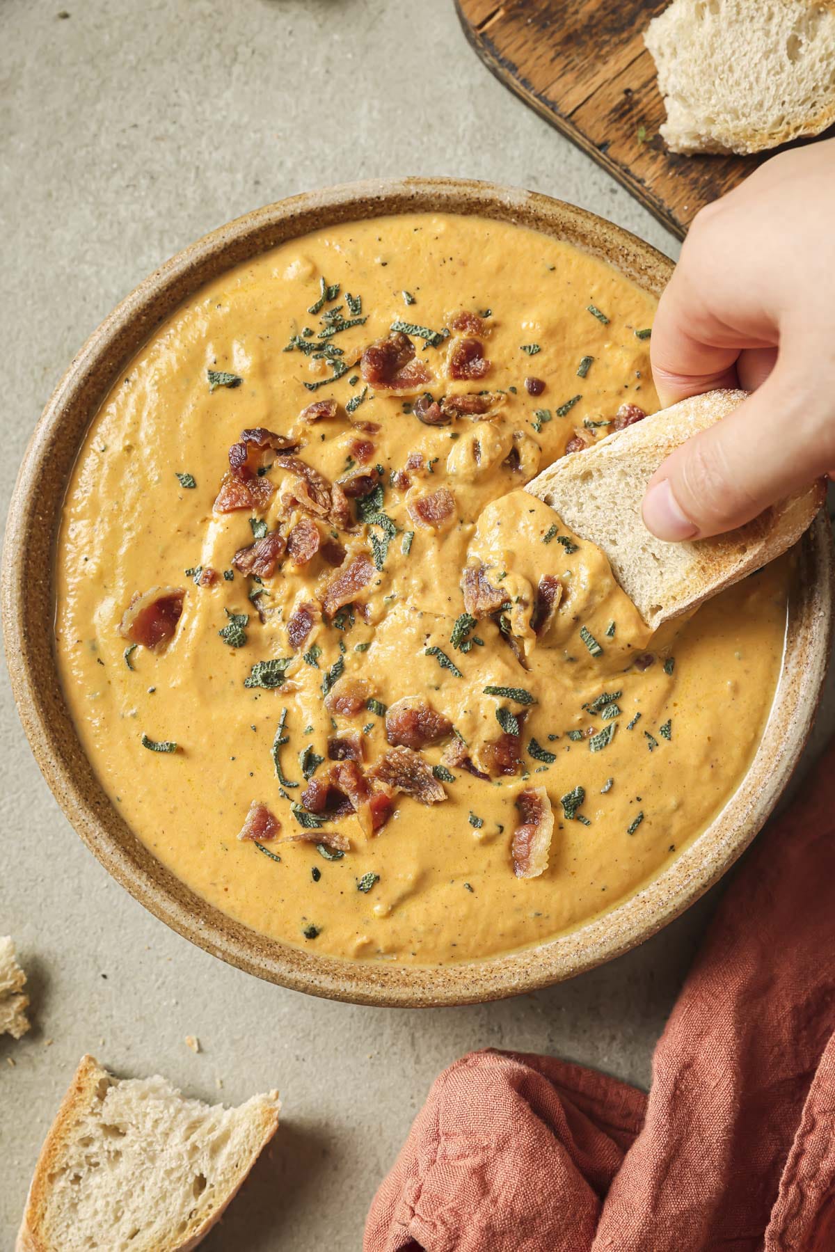 Dipping a small piece of toast into a creamy orange dip.