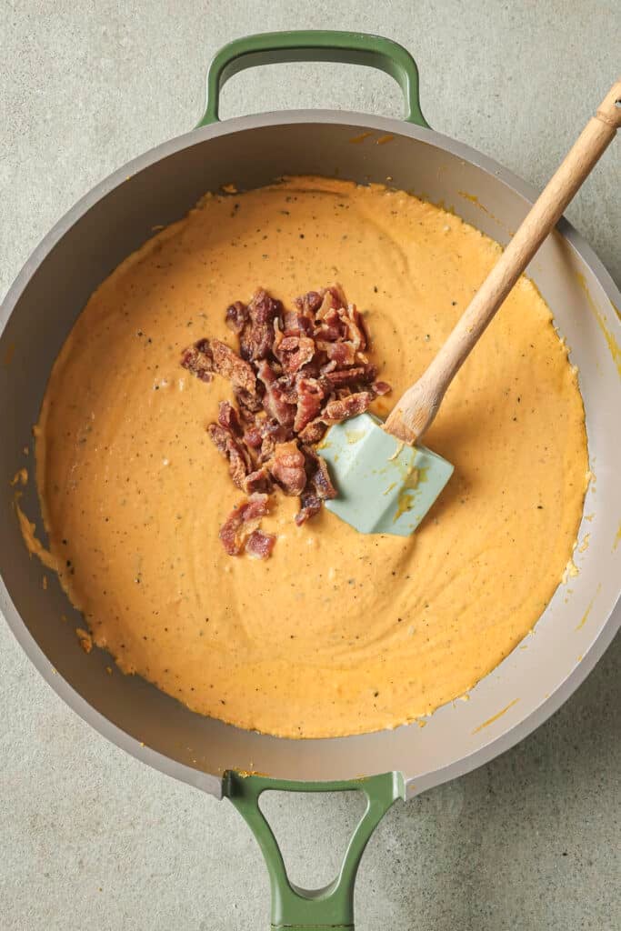 Stirring bacon into creamy pumpkin dip.