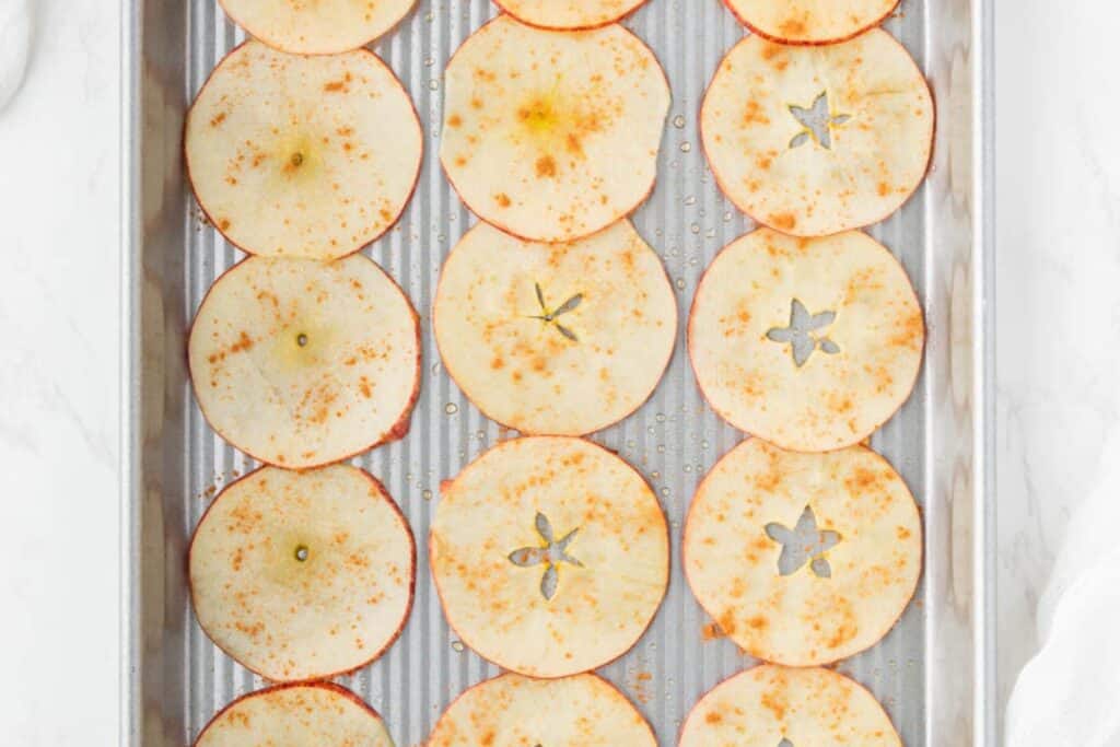 Adding cinnamon to apple slices.
