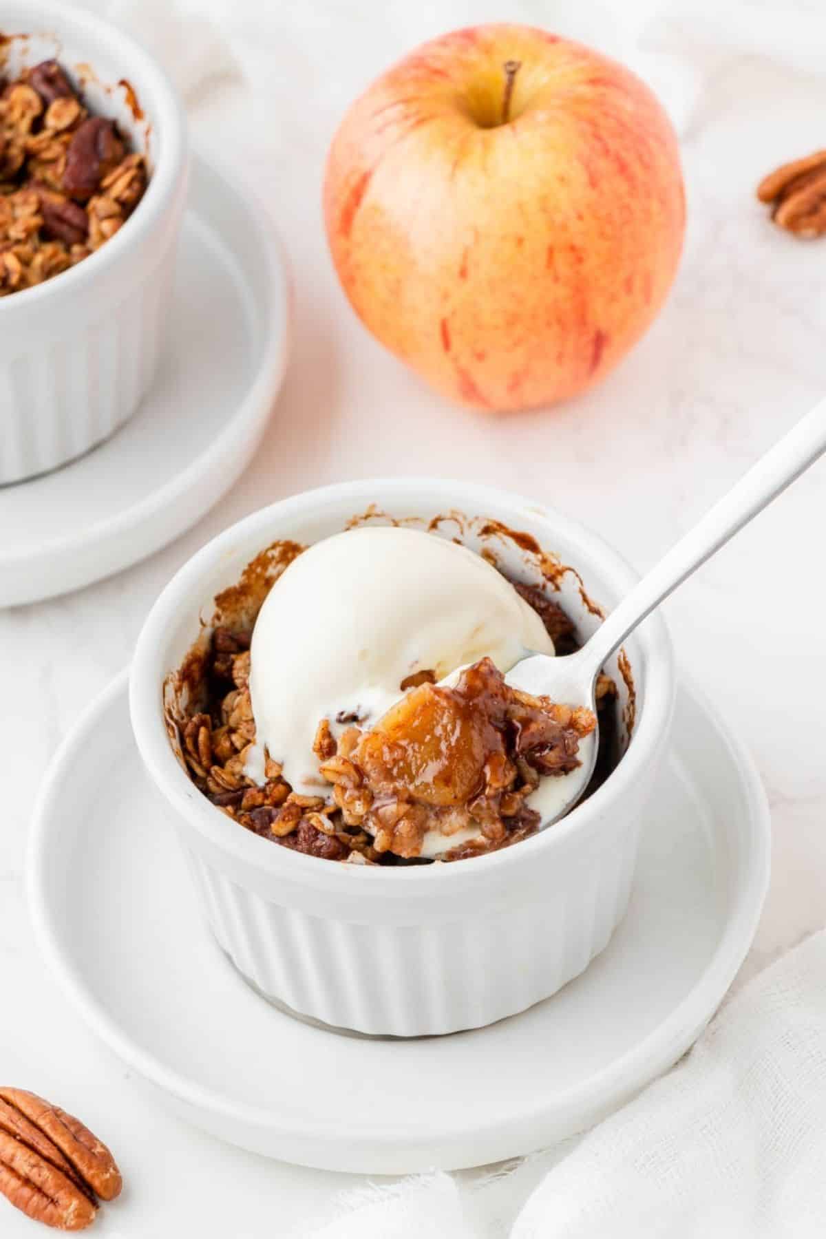 Spoonful of mini air fryer apple crisp topped with vanilla ice cream.