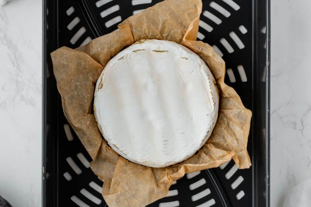 Wheel of brie in the air fryer basket.