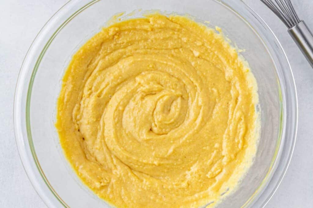 Mixed cornbread batter in a glass mixing bowl.