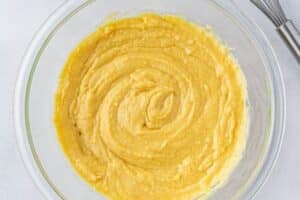 Mixed cornbread batter in a glass mixing bowl.