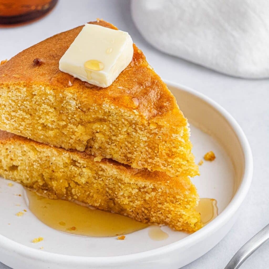 A plate with two slices of cornbread.