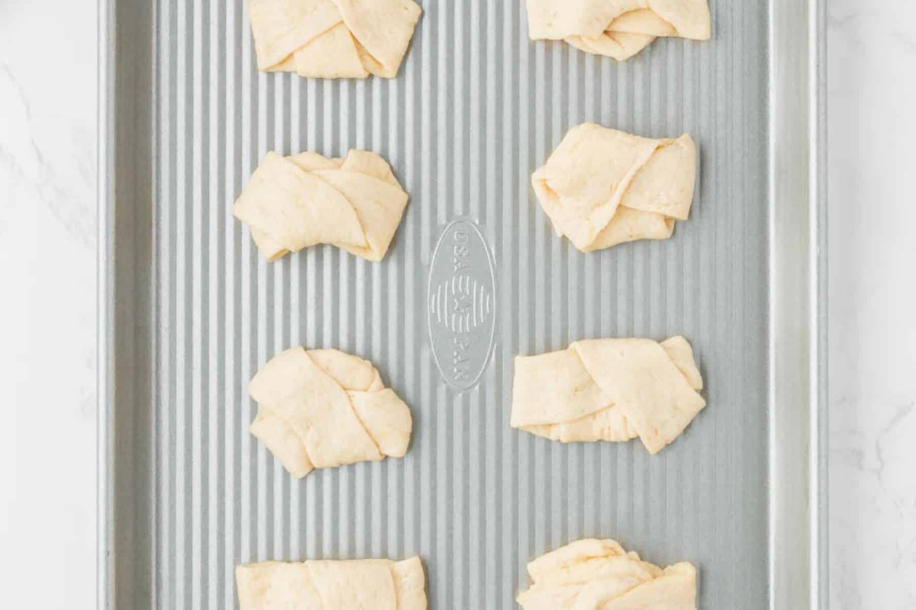 Adding folded dough to a baking sheet.