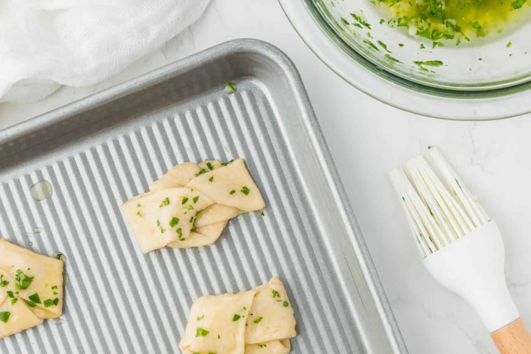 Brushing dough with melted butter and parsley.