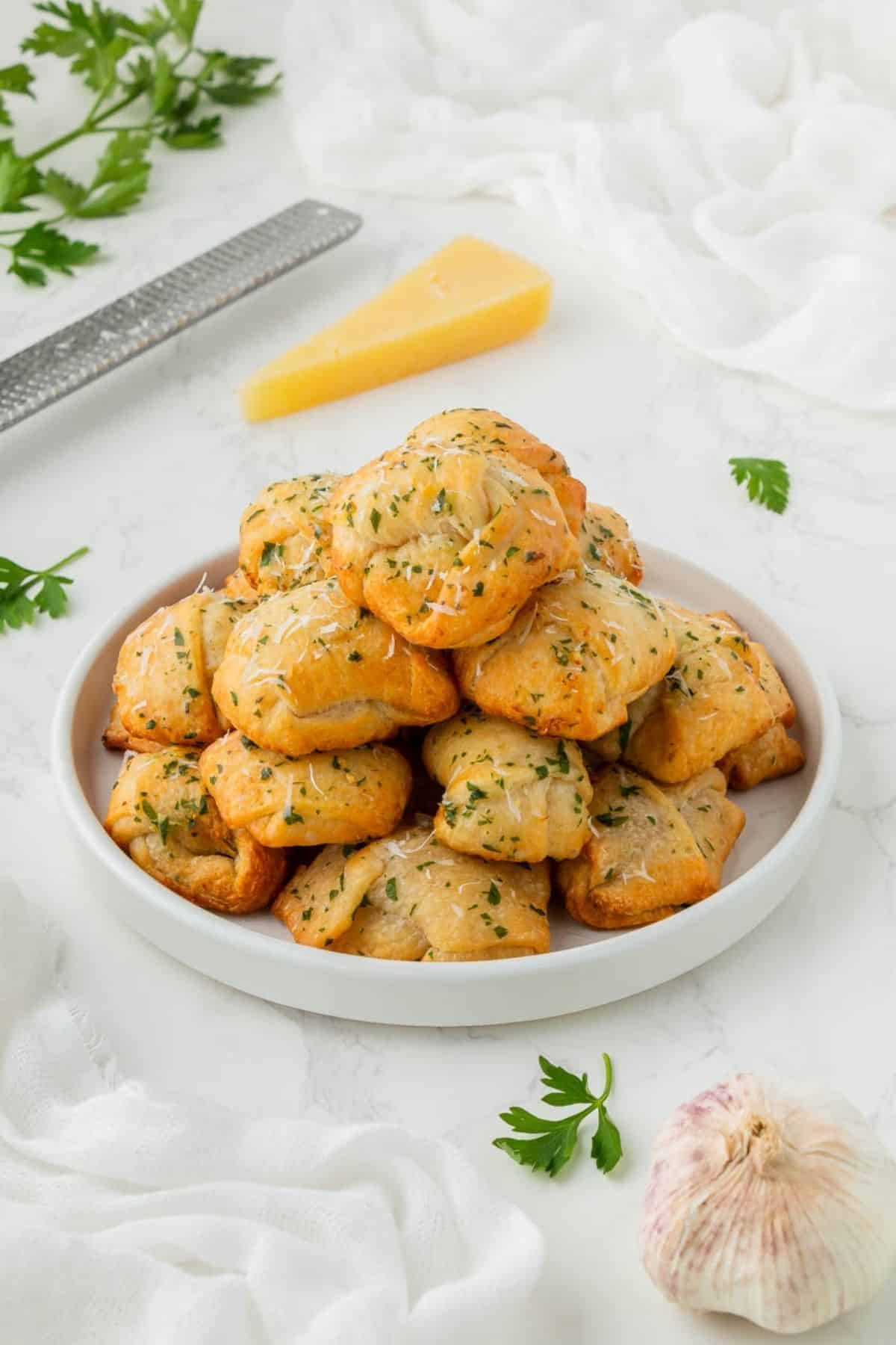 A plate of air fryer garlic knots stacked on top of each other.