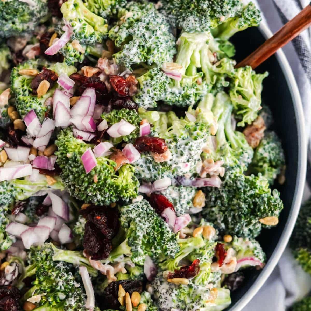 Broccoli salad in a bowl with a white striped napkin.