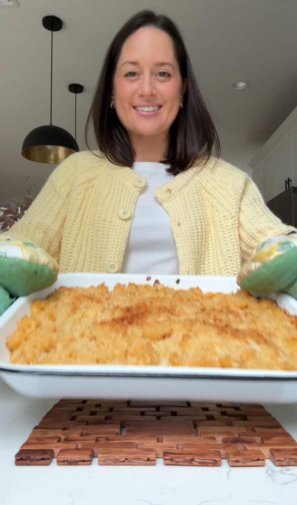 Jordan Zelesnick of JZ Eats holding a white baking dish with buffalo mac and cheese.