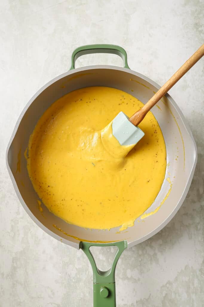 Heating the butternut squash sauce in a saucepan.